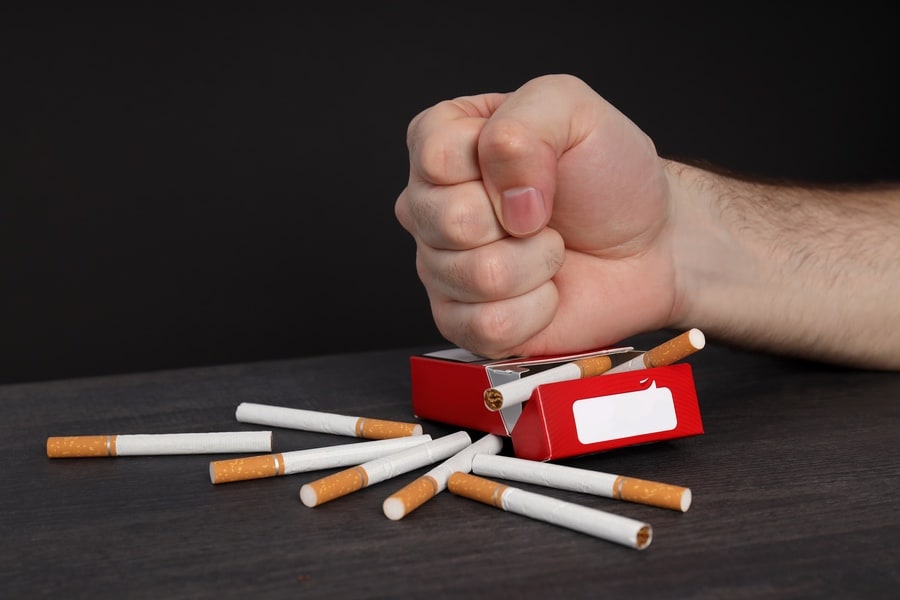 Concept of harm of smoking, male hand and pack of cigarettes